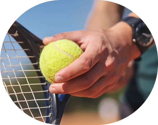 Close-up de um jogador de ténis segurando uma bola de ténis ao lado de uma raquete durante um treino ao ar livre